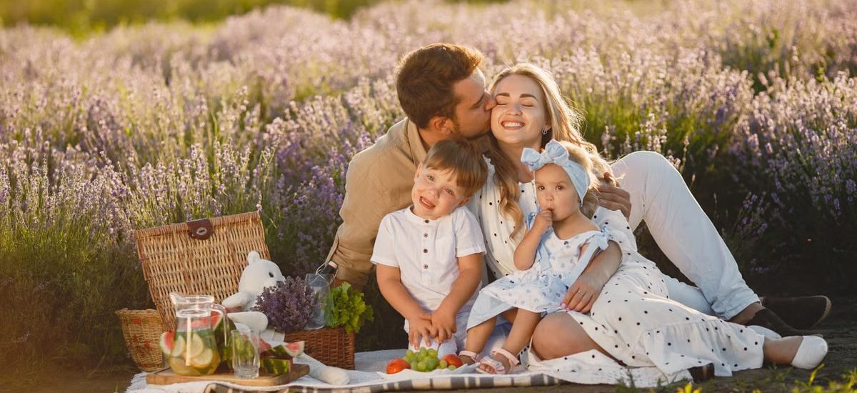 A joyful family enjoying a picnic together in a scenic lavender field during summer.