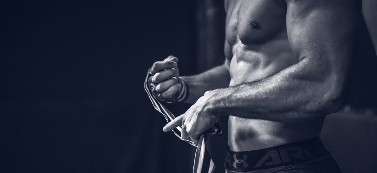 a shirtless man holding a pair of gloves